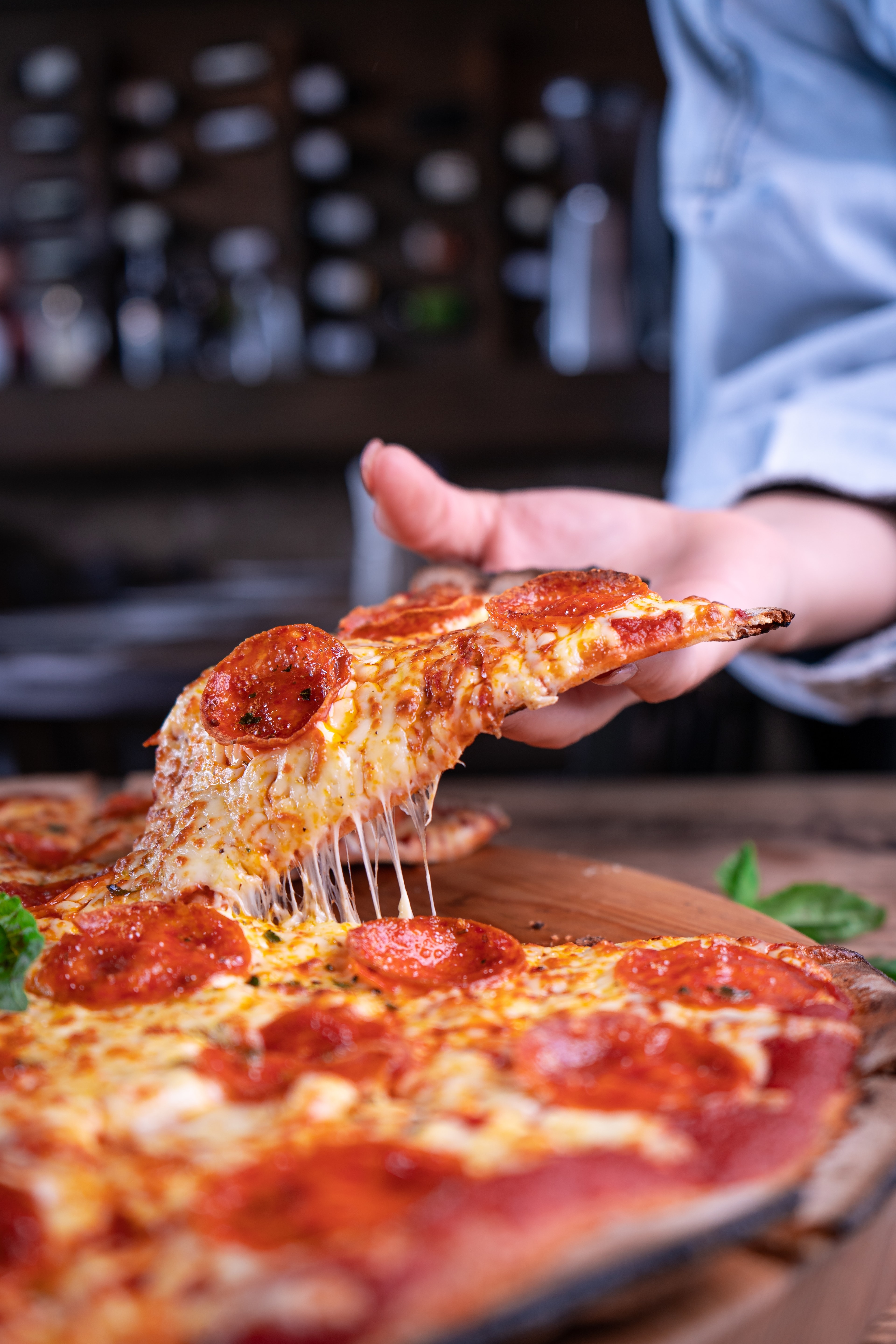 Part de pizza filante tout juste sortie du four, mozzarella qui s'étire